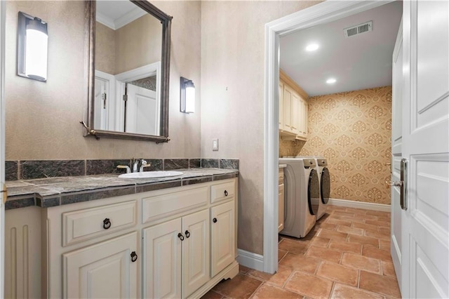 bathroom featuring washing machine and clothes dryer, crown molding, and vanity