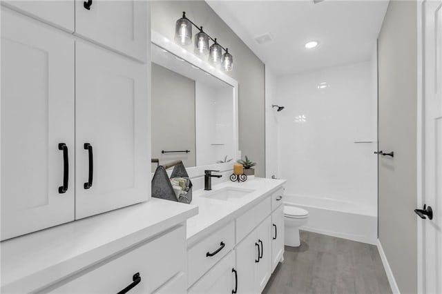 full bathroom with toilet, hardwood / wood-style flooring, vanity, and tub / shower combination