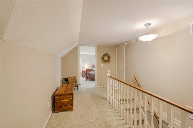 corridor featuring vaulted ceiling and light colored carpet