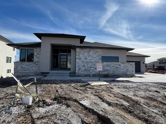 view of front facade with a garage, stone siding, and stucco siding