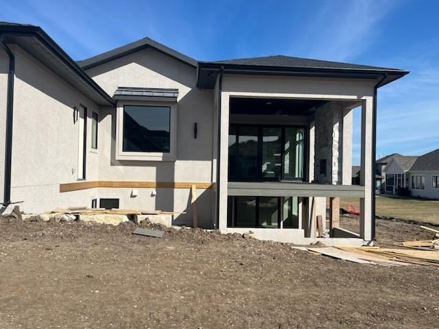 rear view of property with a sunroom and stucco siding