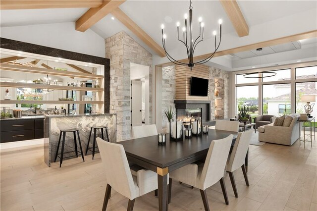 12303 W 167th Ter, Overland Park, KS 66221 - dining area with beam ceiling, a large fireplace, a chandelier, light wood-style flooring, and bar