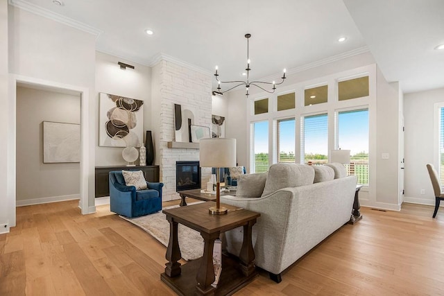 living room featuring a stone fireplace, ornamental molding, light hardwood / wood-style flooring, and a notable chandelier