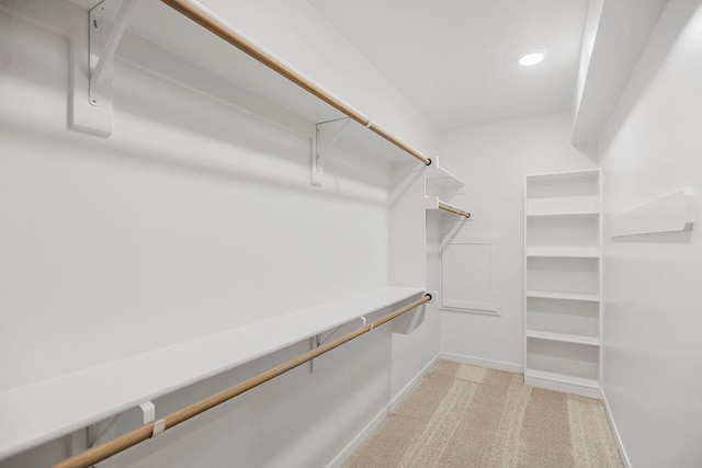 walk in closet with light carpet