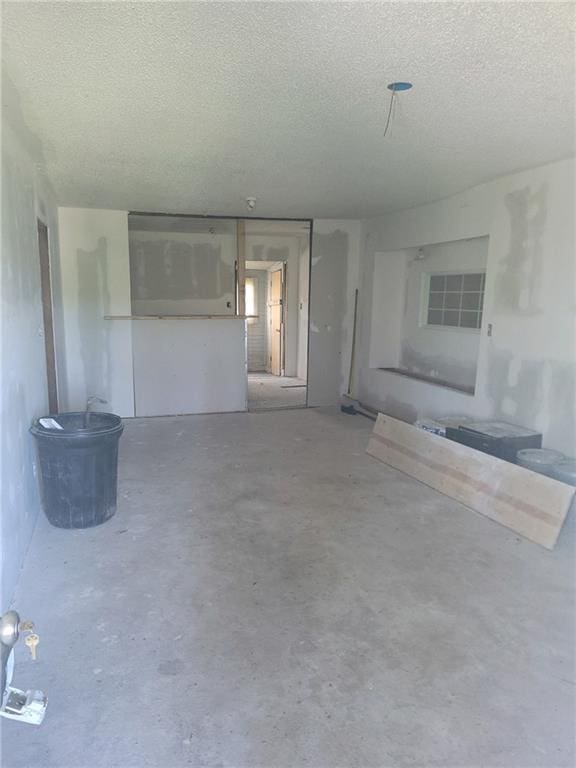 unfurnished living room with a textured ceiling and concrete flooring