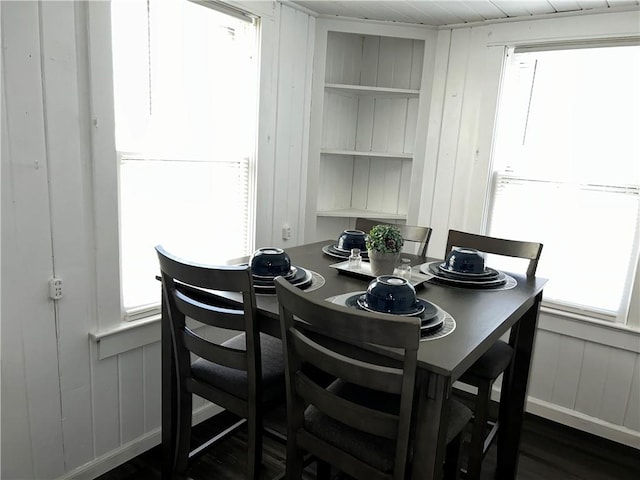 dining room with wood walls, plenty of natural light, and dark hardwood / wood-style floors