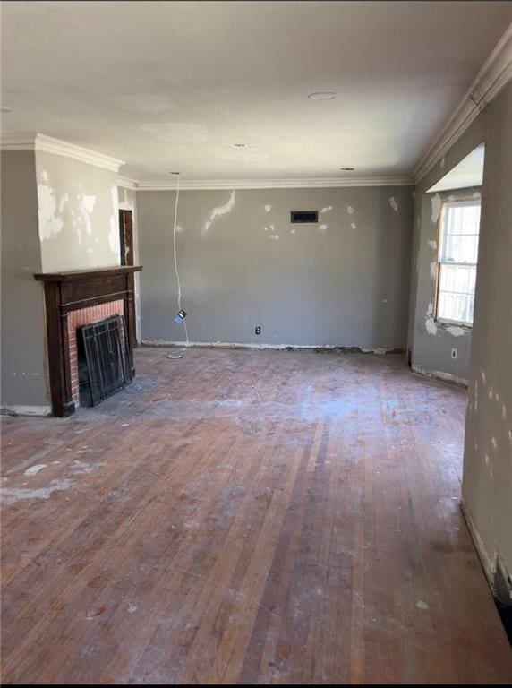 unfurnished living room featuring wood-type flooring, ornamental molding, and a brick fireplace