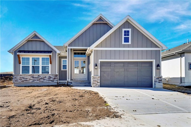 view of front of property with a garage, stone siding, board and batten siding, and driveway