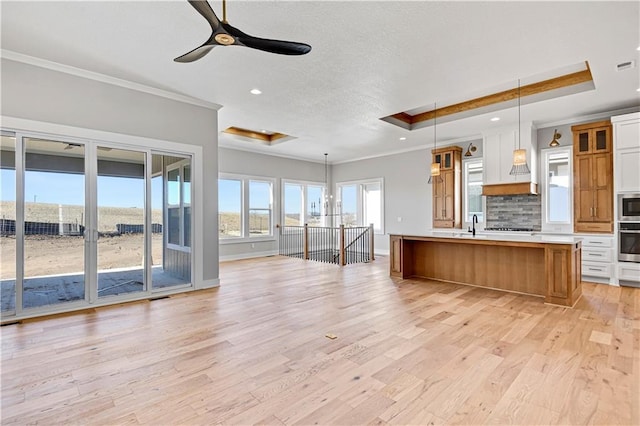 kitchen with tasteful backsplash, open floor plan, a tray ceiling, stainless steel appliances, and crown molding