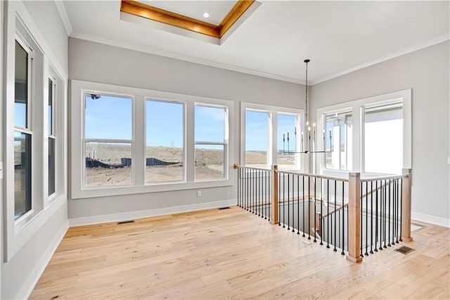 spare room with baseboards, light wood-style floors, visible vents, and crown molding