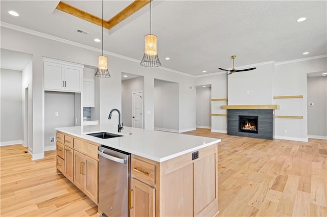 kitchen featuring visible vents, stainless steel dishwasher, light wood-style floors, a sink, and a lit fireplace