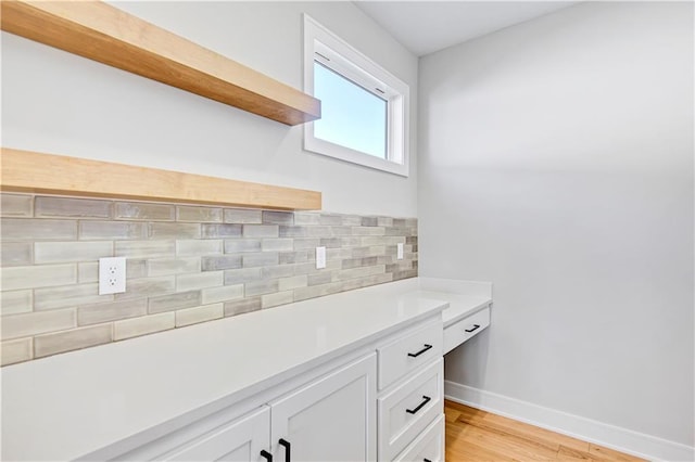 bathroom featuring baseboards, decorative backsplash, and wood finished floors