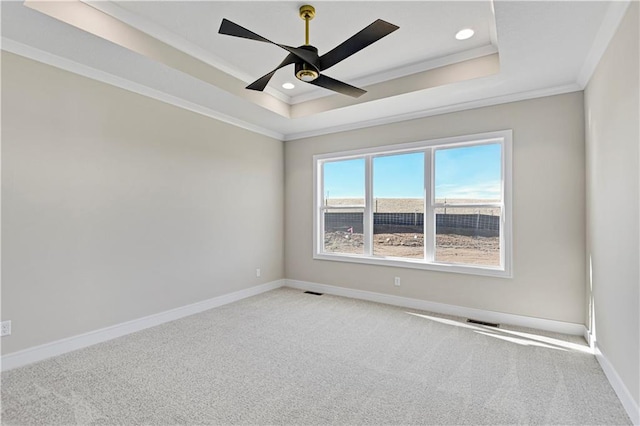 empty room featuring carpet floors, baseboards, a raised ceiling, and crown molding