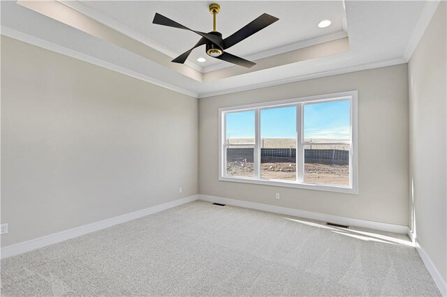 carpeted empty room with crown molding, a tray ceiling, recessed lighting, and baseboards