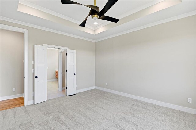 unfurnished bedroom with baseboards, a raised ceiling, and crown molding