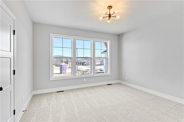 spare room featuring a notable chandelier, visible vents, baseboards, and carpet flooring