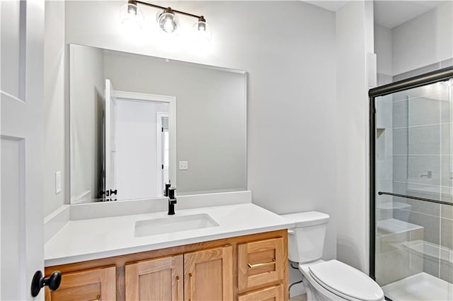 bathroom with vanity, a shower stall, and toilet