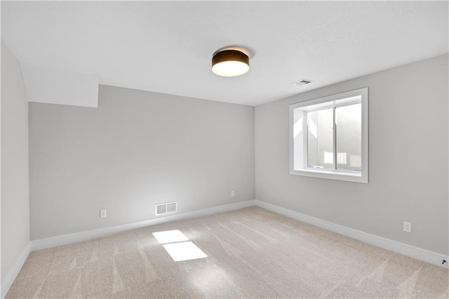 carpeted spare room with visible vents and baseboards