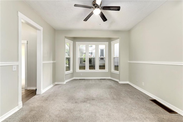 empty room featuring ceiling fan, light colored carpet, and a textured ceiling