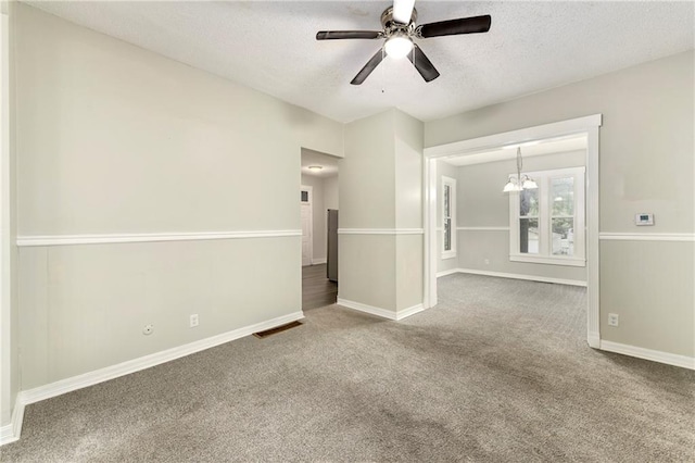 carpeted empty room with a textured ceiling and ceiling fan with notable chandelier