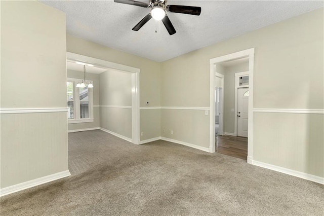 carpeted empty room with ceiling fan with notable chandelier and a textured ceiling