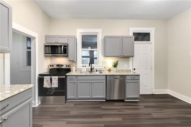 kitchen featuring appliances with stainless steel finishes, dark hardwood / wood-style flooring, gray cabinets, a textured ceiling, and sink