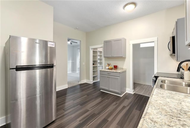 kitchen featuring sink, a textured ceiling, gray cabinets, appliances with stainless steel finishes, and dark hardwood / wood-style flooring