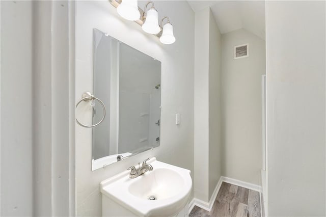 bathroom with vaulted ceiling, hardwood / wood-style flooring, and sink