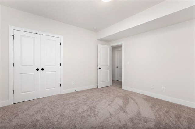 unfurnished bedroom with light carpet and a closet