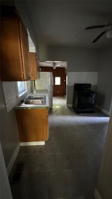 kitchen with black / electric stove, sink, ceiling fan, and dark tile patterned floors