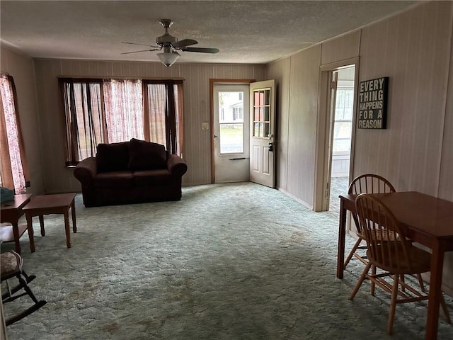 carpeted living room featuring ceiling fan and a textured ceiling