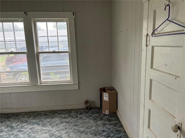 carpeted empty room featuring wooden walls