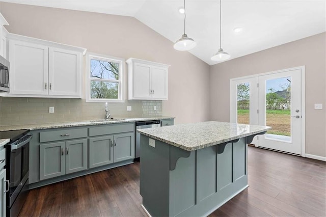 kitchen featuring appliances with stainless steel finishes, a sink, a center island, backsplash, and vaulted ceiling