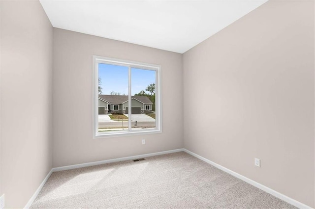 carpeted spare room featuring baseboards and visible vents