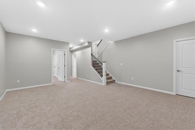 finished basement with stairway, baseboards, light carpet, and recessed lighting