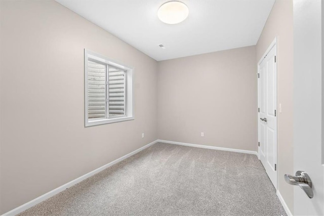 carpeted spare room featuring baseboards