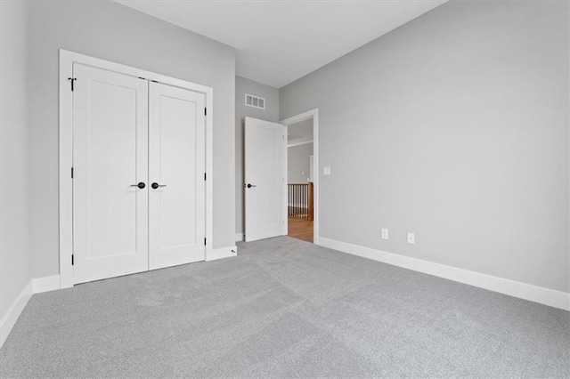 unfurnished bedroom with a closet and light colored carpet