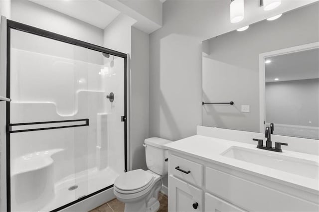 bathroom featuring toilet, vanity, tile patterned flooring, and a shower with shower door