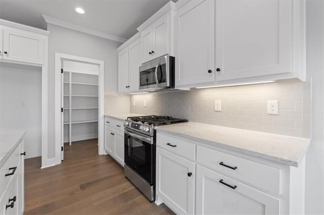 kitchen featuring light stone counters, crown molding, stainless steel appliances, dark hardwood / wood-style flooring, and white cabinets