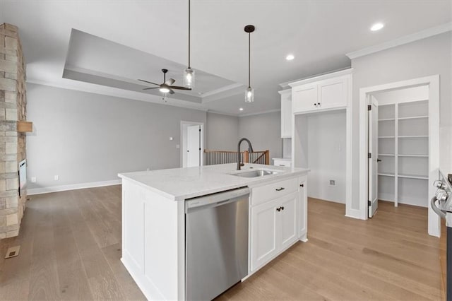 kitchen with white cabinets, a center island with sink, dishwasher, and a tray ceiling