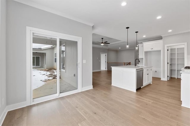 kitchen featuring stainless steel dishwasher, decorative light fixtures, an island with sink, and white cabinetry