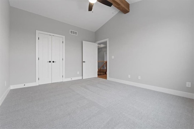 unfurnished bedroom with ceiling fan, lofted ceiling with beams, carpet, and a closet