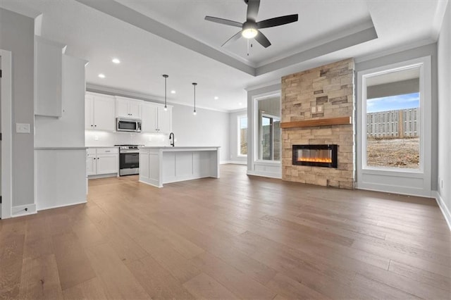 unfurnished living room featuring a fireplace, light wood-type flooring, crown molding, and a sink
