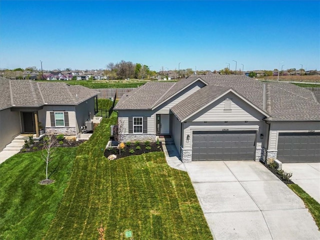 single story home with stone siding, an attached garage, a front yard, and concrete driveway