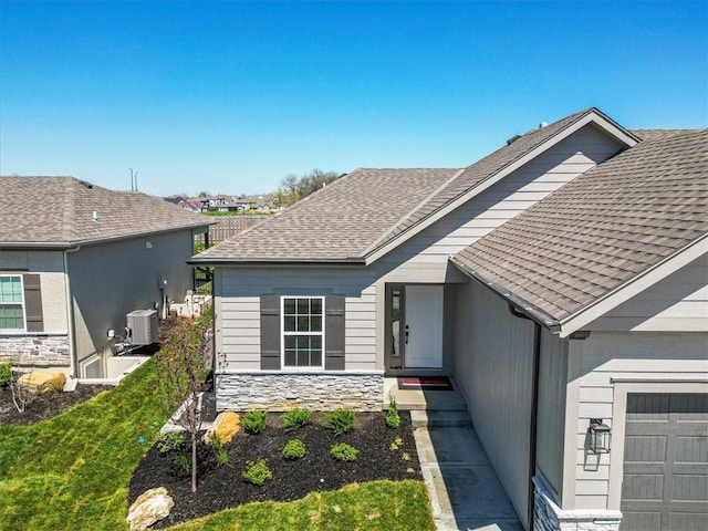 25026 W 94th Ter, Lenexa, KS 66227 - doorway to property featuring central AC, stone siding, and roof with shingles