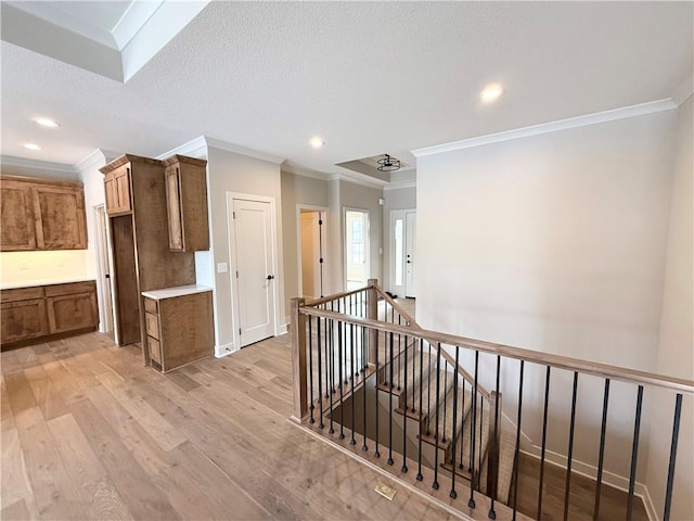 hall with crown molding, light hardwood / wood-style flooring, and a textured ceiling