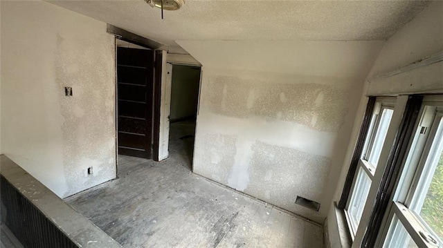 empty room with a textured ceiling and vaulted ceiling