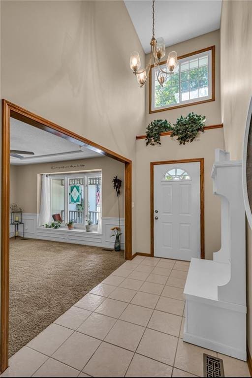 carpeted entrance foyer with a notable chandelier and a towering ceiling