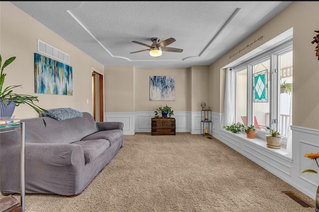 carpeted living room with a textured ceiling and ceiling fan