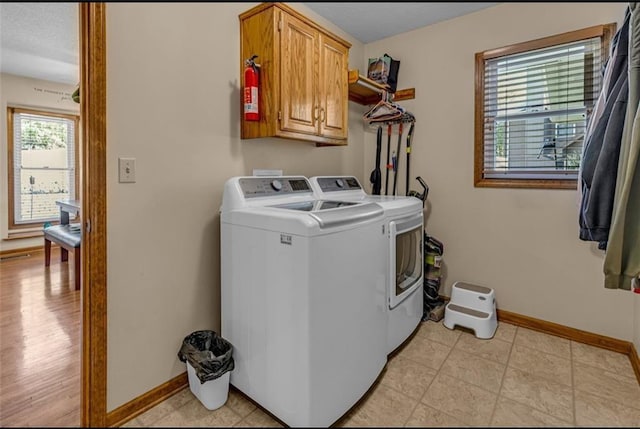 washroom featuring separate washer and dryer, light hardwood / wood-style flooring, and cabinets